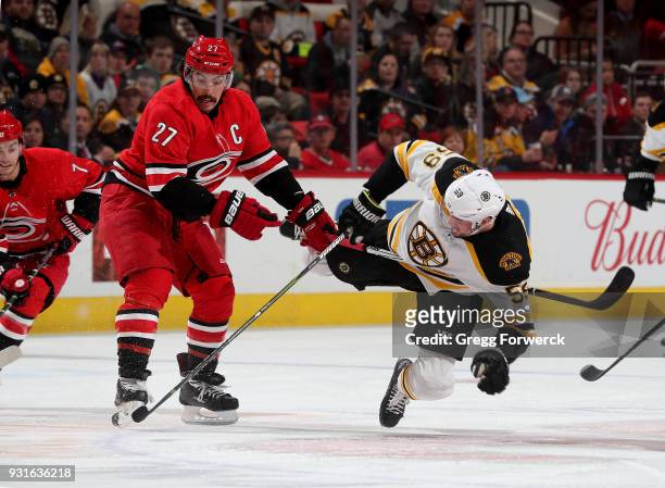 Justin Faulk of the Carolina Hurricanes and Tim Schaller of the Boston Bruins battle to control the puck during an NHL game on March 13, 2018 at PNC...