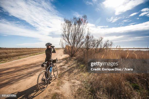 female cyclist with binoculars in the delta del ebro - delta ebro fotografías e imágenes de stock