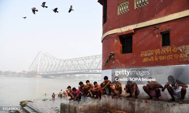 Local people seen brushing their teeth next to the Howrah bridge in Kolkata. The Rabindra Setu also known as the Howrah bridge is a bridge with a...