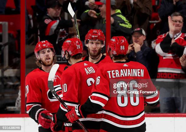 Sebastian Aho of the Carolina Hurricanes is congratulated by teammates Elias Lindholm, Jordan Staal and Teuvo Teravainen after scoring a goal during...