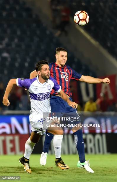 Uruguay's Defensor Sporting player Ernesto Goni ies for the ball with Paraguay's Cerro Porteno player Diego Churin during their 2018 Copa...