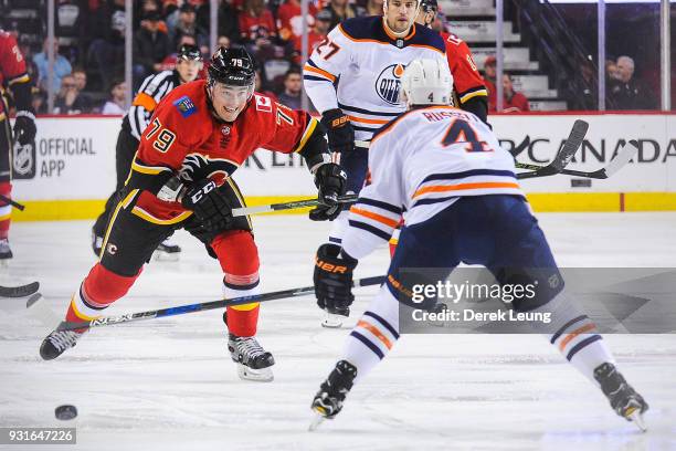 Micheal Ferland of the Calgary Flames chases the puck against Kris Russell of the Edmonton Oilers during an NHL game at Scotiabank Saddledome on...