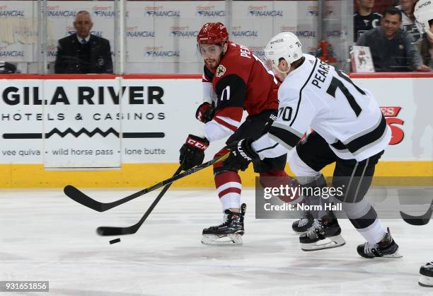 Brendan Perlini of the Arizona Coyotes passes the puck under the stick of Tanner Pearson of the Los Angeles Kings during the first period at Gila...