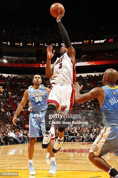 Dwyane Wade of the Miami Heat goes up for a shot against Malik Allen and Chauncey Billups of the Denver Nuggets during the game at American Airlines...