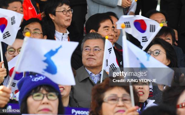 South Korean President Moon Jae-in is seen as spectators wave the national flag and "unification flags" during the men's 1.1km sprint sitting...