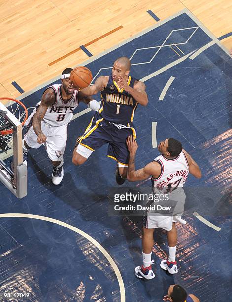 Dahntay Jones of the Indiana Pacers drives in between Terrence Williams and Chris Douglas-Roberts of the New Jersey Nets during a game on November...