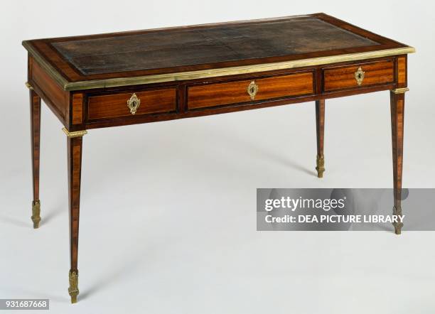 Bois de rose and rosewood veneered writing desk with leather-covered top and gilt bronze edging, France, late 18th century.