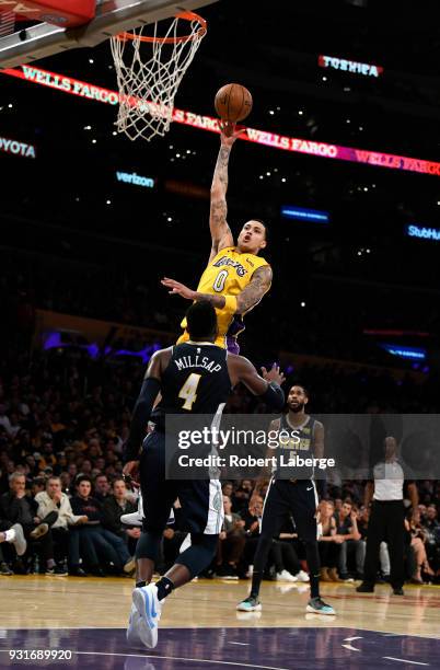 Kyle Kuzma of the Los Angeles Lakers attempts a shot against Paul Millsap of the Denver Nuggets on March 13, 2018 at STAPLES Center in Los Angeles,...