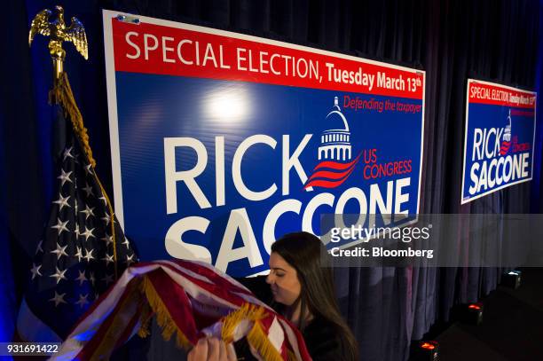 An attendee prepares a flag on a stage ahead of an election night rally with Rick Saccone, Republican candidate for the U.S. House of...