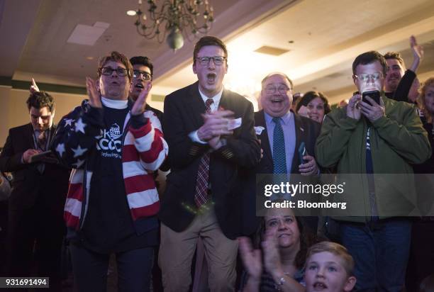 Attendees applaud and cheer while watching polling results during an election night rally with Rick Saccone, Republican candidate for the U.S. House...