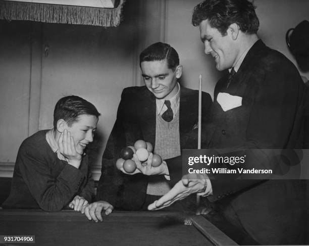 English boxer Freddie Mills shows Jack Carney and Colin Smith his trick of holding 12 snooker balls in one hand at the semi-finals of the boys'...