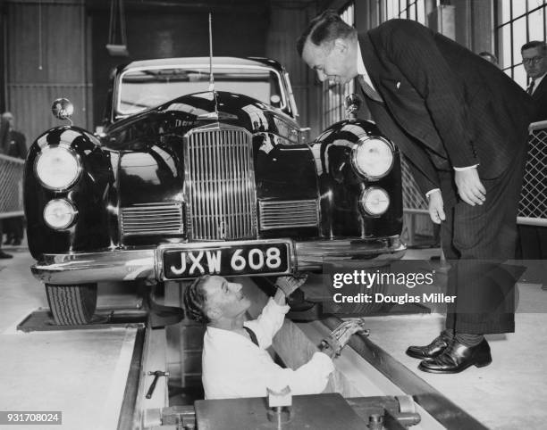 John Boyd-Carpenter , the Minister of Transport and Civil Aviation chats to J. Gordon Doyle in the pit, while Doyle tests his Humber car in the first...