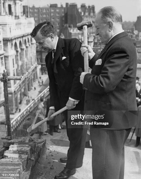 John Boyd-Carpenter , the Minister of Transport and Civil Aviation, and Trevor A. Bowen , chairman of the Barker Group, begin a demolition project on...