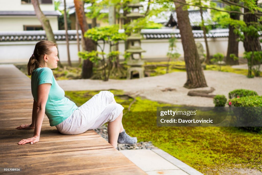 Seitenansicht der Frau sitzen auf Tempel Podium und genießen Zen-Garten von Chion-Ji-Tempel in Kyoto, Japan