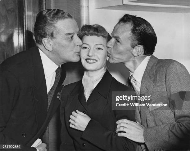 English-born actress, singer and dancer Jeannie Carson receives a kiss from actors Jack Buchanan and Frank Sinatra during a Variety Club luncheon in...