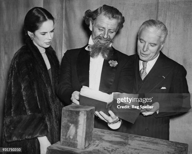 English actor and filmmaker Charlie Chaplin and his wife Oona visit actor Emlyn Williams on the stage of the Ambassador's Theatre in London, where...