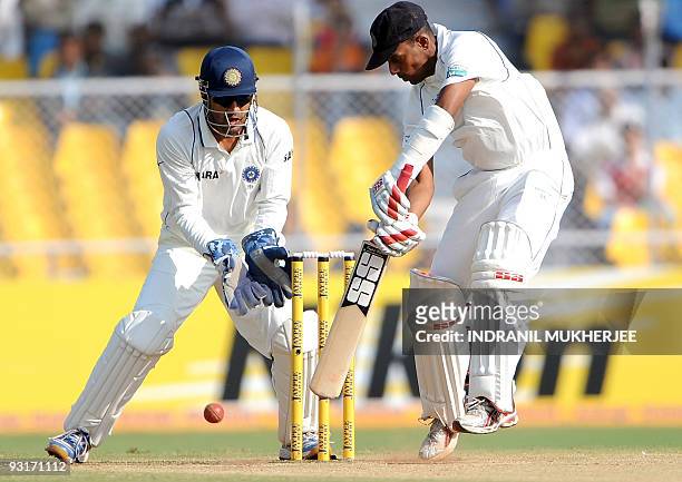 Indian cricketer Mahendra Singh Dhoni looks on as Sri Lankan cricketer Thilan Samaraweera batson the third day of the first test between India and...