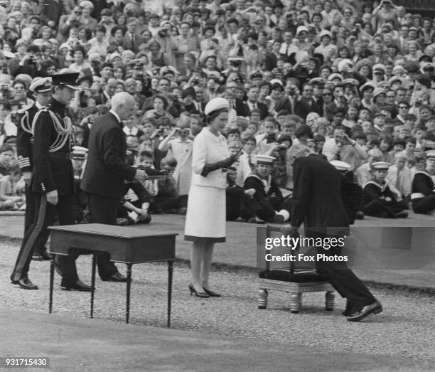 Sir Francis Chichester is knighted by Queen Elizabeth II at Greenwich in London, after becoming the first person to sail single-handed around the...