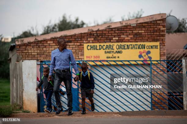 Parent walks out of the Childcare Orientation Centre in Klipspruit West, in Soweto, with his children on March 13, 2017. Nine children under the age...