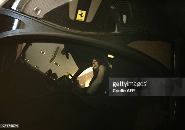 Woman is reflected on a Ferrari helmet as she inspects one of the cars at the luxury car maker's showroom in downtown Beirut on November 5, 2009....