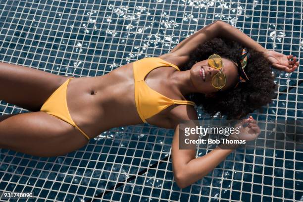 mixed race woman sunbathing on a luxury yacht - badebekleidung stock-fotos und bilder