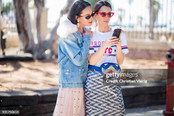 Anna Aronov wearing denim jacket and Meital Katz wearing white tshirt with Brooklyn printed, metallic midi skirt, Gucci fanny bag is seen during Tel...