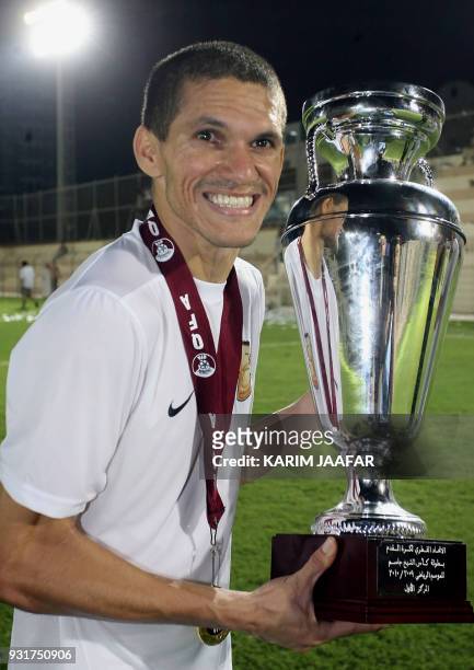 Umm Salal's Brazilian striker Magno Alves celebrates with the trophy after winning the Sheikh Jassem Cup following the final football match against...