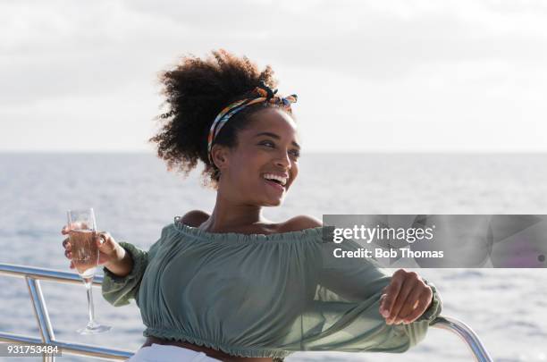 young mixed race woman enjoying a glass of champagne on a luxury yacht - brown hair drink wine stock-fotos und bilder