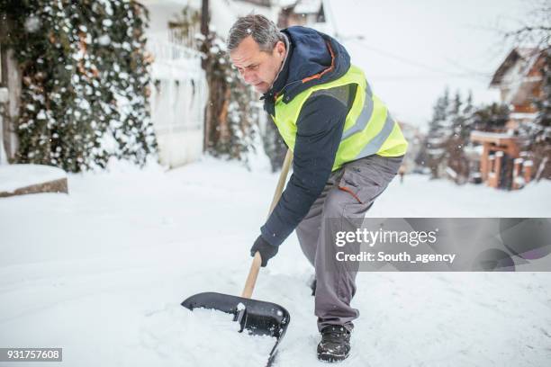 man cleaning snow on the street - older man snow shovel stock pictures, royalty-free photos & images