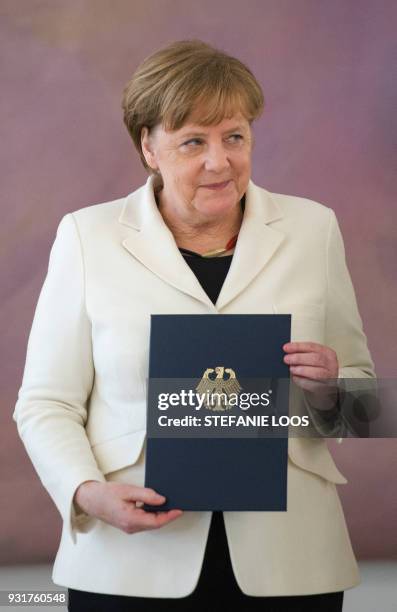 German Chancellor Angela Merkel holds her certificate of appointment she was given by the German President on March 14, 2018 at Bellevue Palace in...