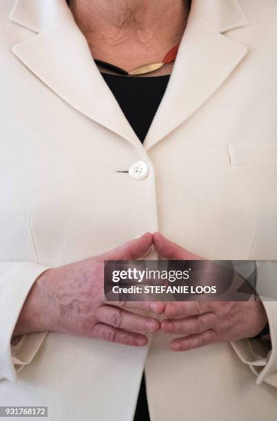 German Chancellor Angela Merkel holds her hands in her typical "Merkel-Raute" position and wears her necklace in the colors of Germany that became...