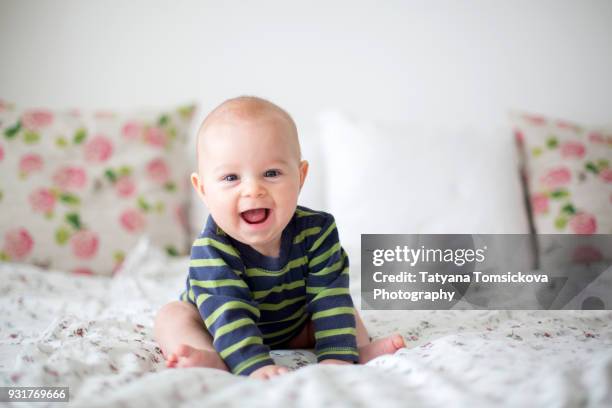 cute little four month old baby boy, playing at home in bed in bedroom, soft back light behind him - baby happy cute smiling baby only stock pictures, royalty-free photos & images