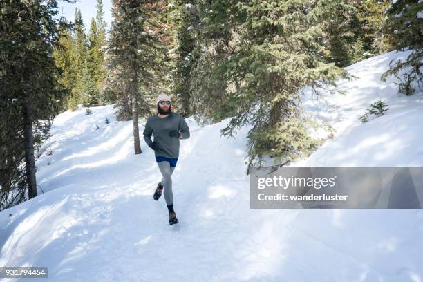 man running on snowy trails in forest - running spikes stock pictures, royalty-free photos & images