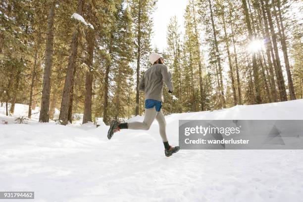 man running on snowy trails in forest - running spikes stock pictures, royalty-free photos & images