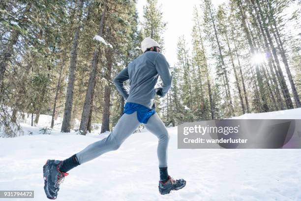 man running on snowy trails in forest - running spikes stock pictures, royalty-free photos & images