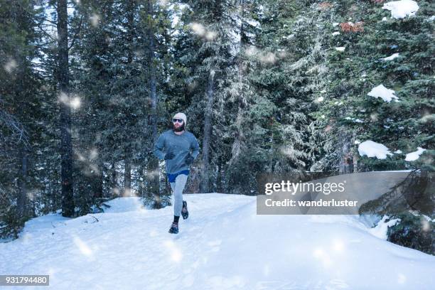 man running during snow fall in forest - running spikes stock pictures, royalty-free photos & images