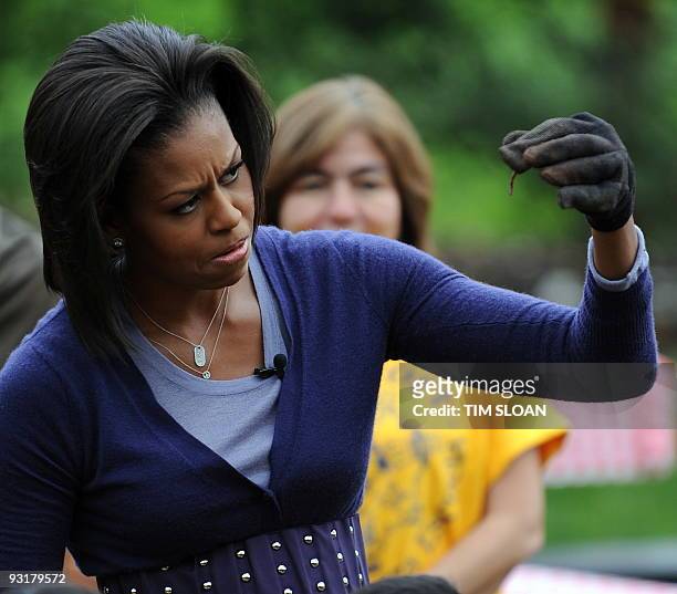 First lady Michelle Obama eyes an earth worm while hosting a fall harvest of the White House vegetable garden with help of students from Washington's...