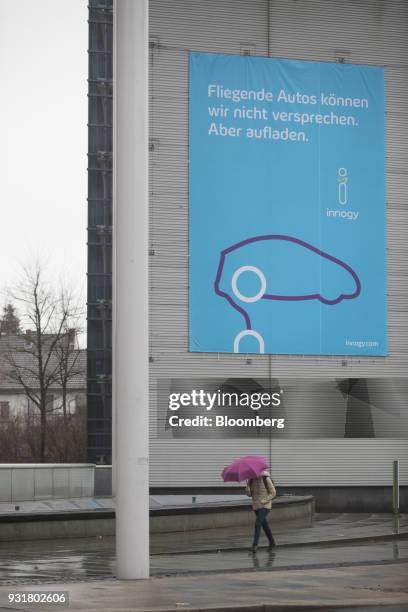 Pedestrian shelters beneath an umbrella outside the headquarters of Innogy SE in Essen, Germany, on Tuesday, March 13, 2018. EON SE will shed as many...