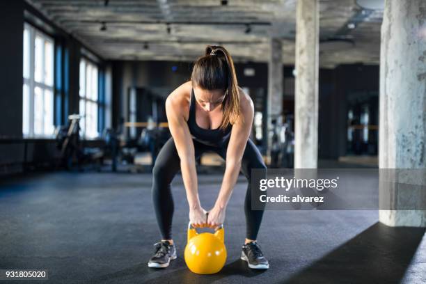 giovane donna che solleva kettlebell in palestra - retrieving foto e immagini stock