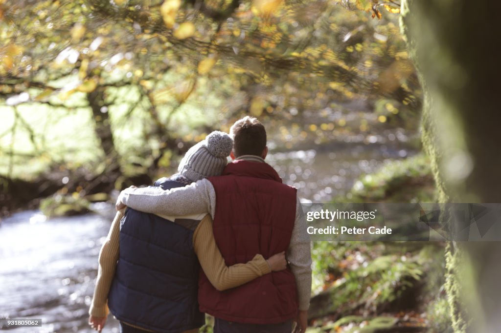 Couple walking in woodland next to river
