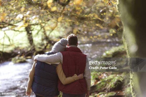 couple walking in woodland next to river - mourning stock pictures, royalty-free photos & images