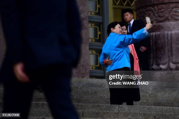 Two delegates use a mobile phone to take a picture as they arrive for the fourth plenary session of the Chinese People's Political Consultative...