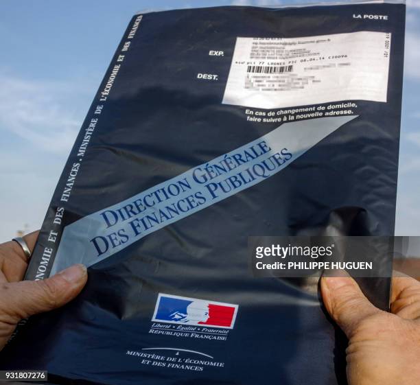 Une personne présentente l'enveloppe contenant la déclaration d'impôts envoyée aux contribuables par le ministère de l'Economie et des Finances, le...