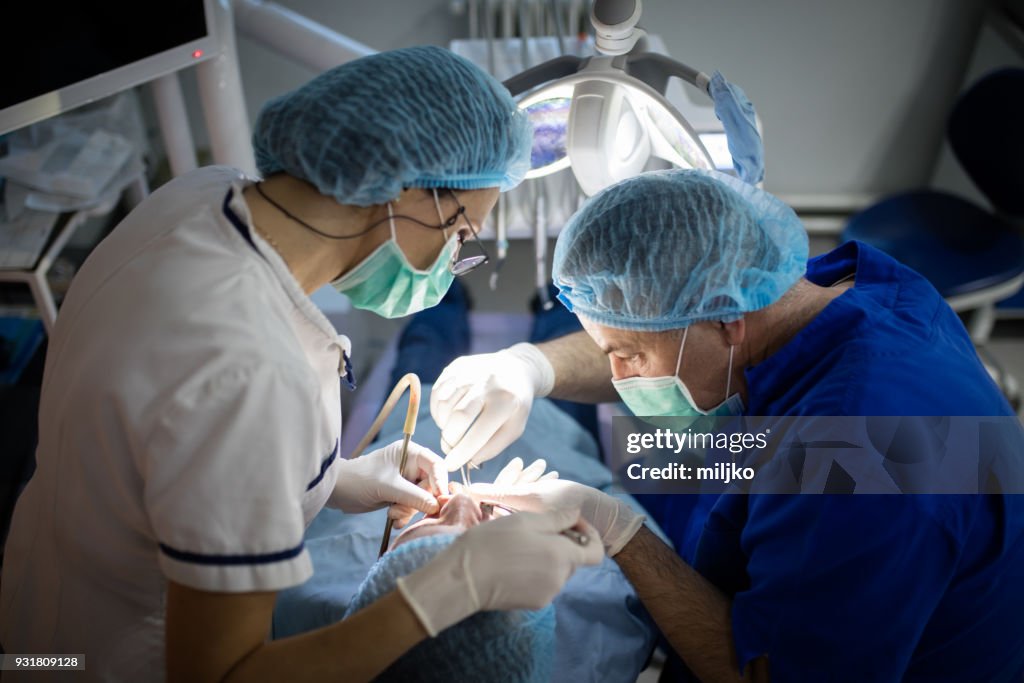 Dentist examining patient and doing dental surgery