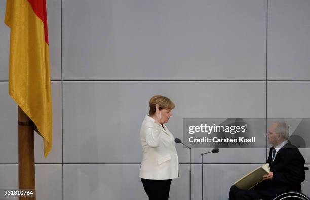 German Chancellor Angela Merkel takes her oath to serve her fourth term as chancellor as Bundestag President Wolfgang Schaeuble holds up a copy of...