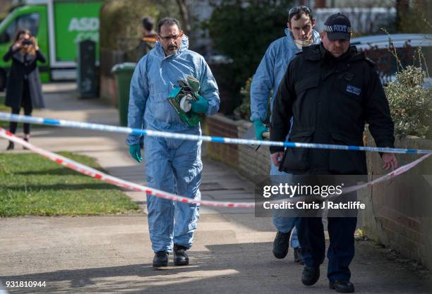 Police forensics officers carry a shovel and other gardening tools into a forensics tent outside the home of Russian exile Nikolai Glushkov who was...