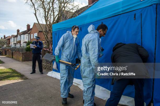 Police forensics officers carry a shovel and other gardening tools into a forensics tent outside the home of Russian exile Nikolai Glushkov who was...