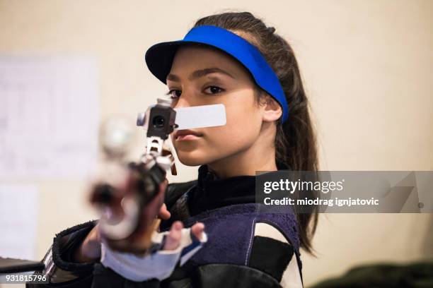 a woman pointing a gun at the camera - air gun stock pictures, royalty-free photos & images