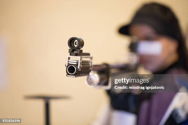 a woman pointing a gun at the camera - air gun stock pictures, royalty-free photos & images