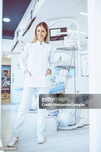 young smiling beautiful dentist posing in dental office - medical footwear stock pictures, royalty-free photos & images